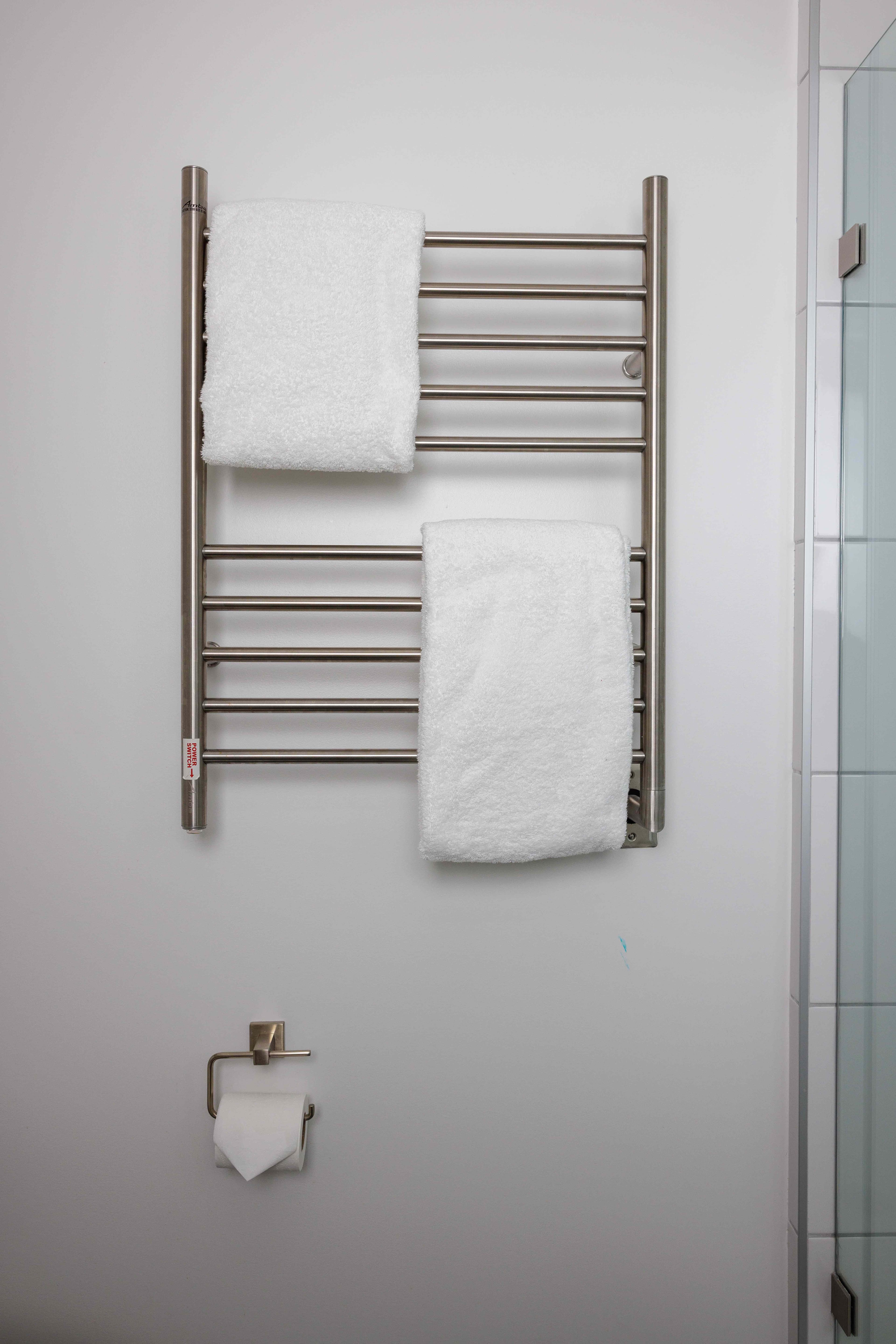 Freshly folded towels on a heated towel rack in an Airbnb bathroom