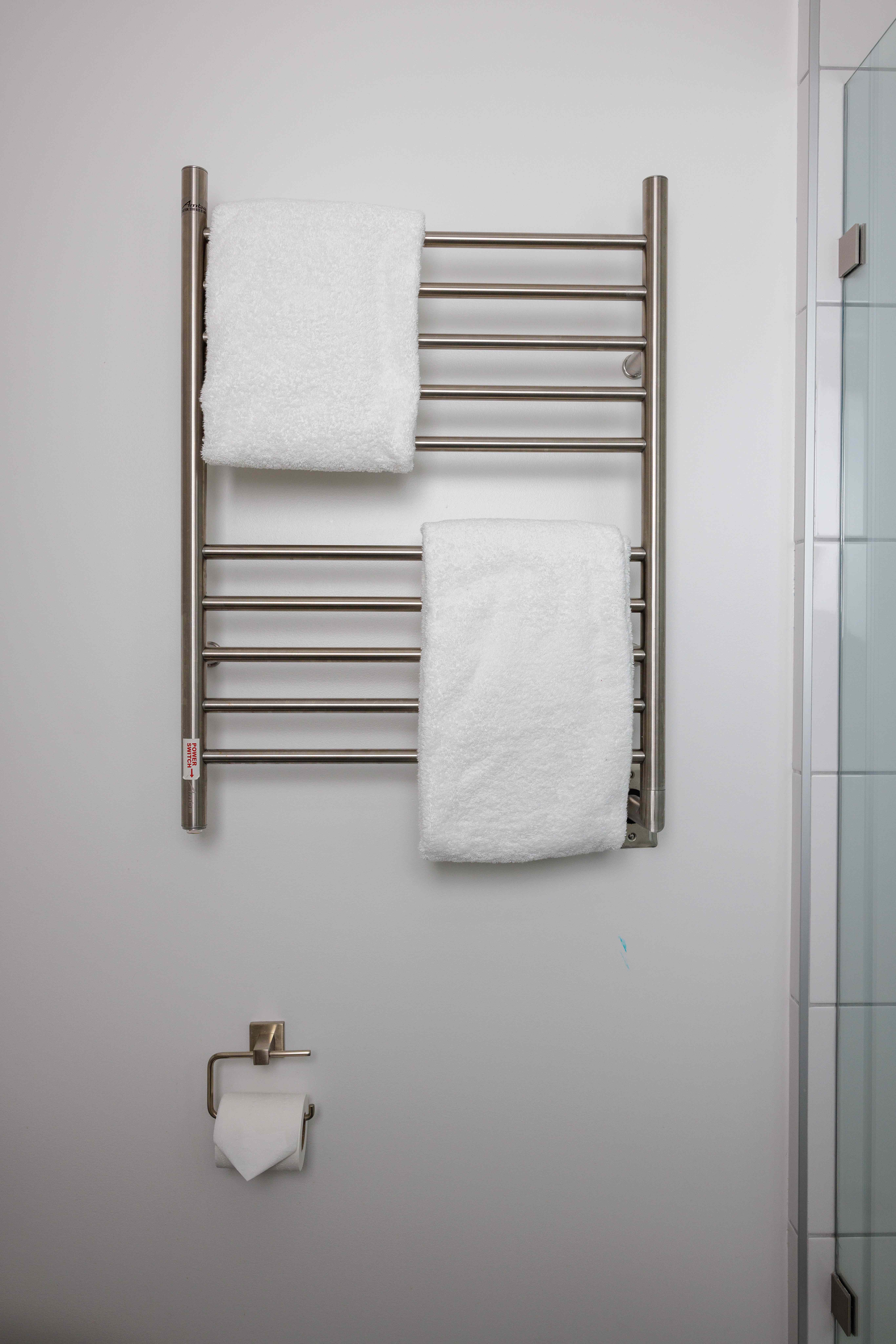 Freshly folded towels on a heated towel rack in an Airbnb bathroom